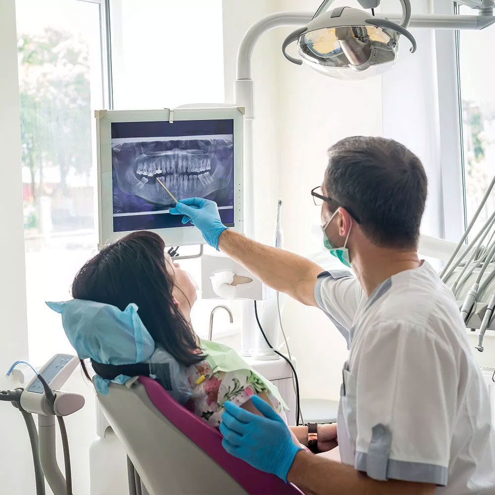 A dental professional is assisting a patient with a digital display of the patient s mouth, highlighting dental work in progress.